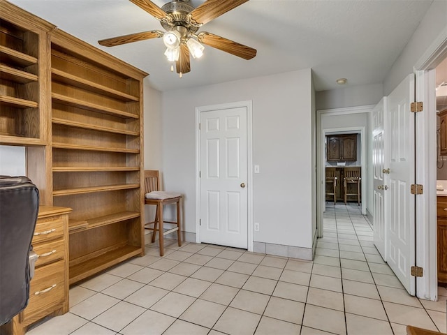 unfurnished office with light tile patterned floors, baseboards, and ceiling fan