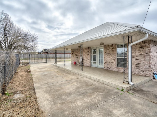 exterior space with a patio area, brick siding, metal roof, and fence