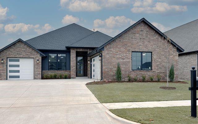 view of front facade with driveway, a front lawn, roof with shingles, an attached garage, and brick siding