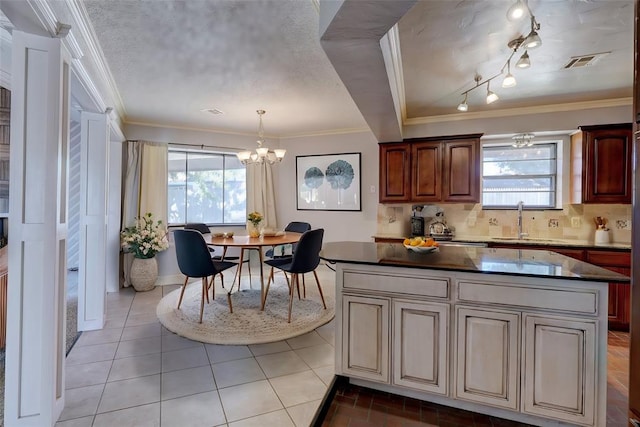 kitchen with dark countertops, crown molding, visible vents, and a sink