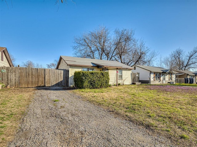 view of side of home featuring a yard, driveway, and fence