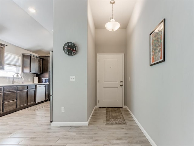 entryway with a sink, baseboards, and light wood finished floors