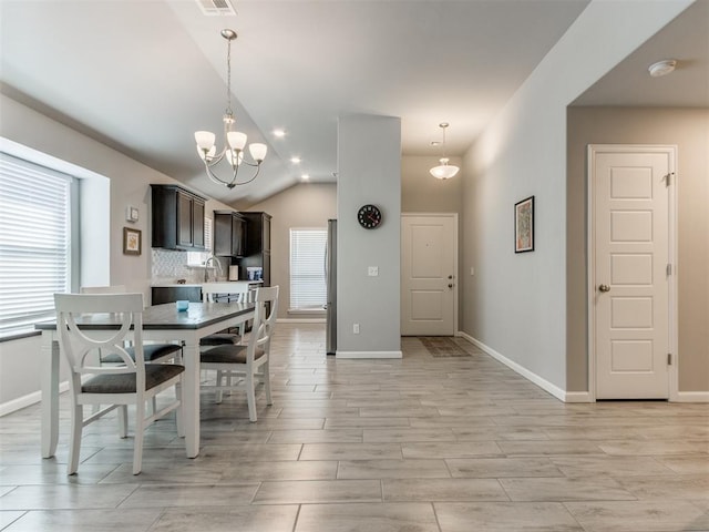 dining area with an inviting chandelier, light wood-type flooring, baseboards, and lofted ceiling