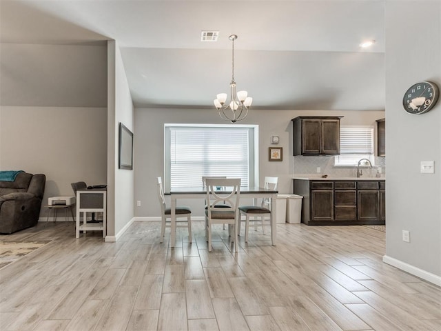 dining area featuring visible vents, baseboards, a chandelier, and light wood finished floors