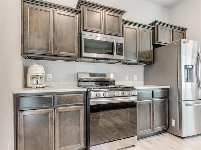 kitchen featuring light wood-style flooring, backsplash, appliances with stainless steel finishes, light countertops, and dark brown cabinets