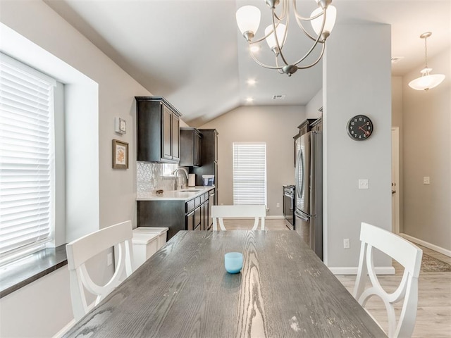 dining area with lofted ceiling, light wood-style flooring, and baseboards