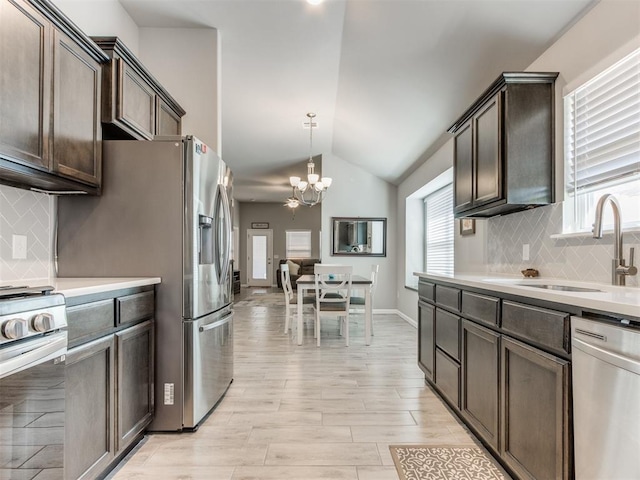 kitchen featuring dark brown cabinetry, vaulted ceiling, stainless steel appliances, and a sink