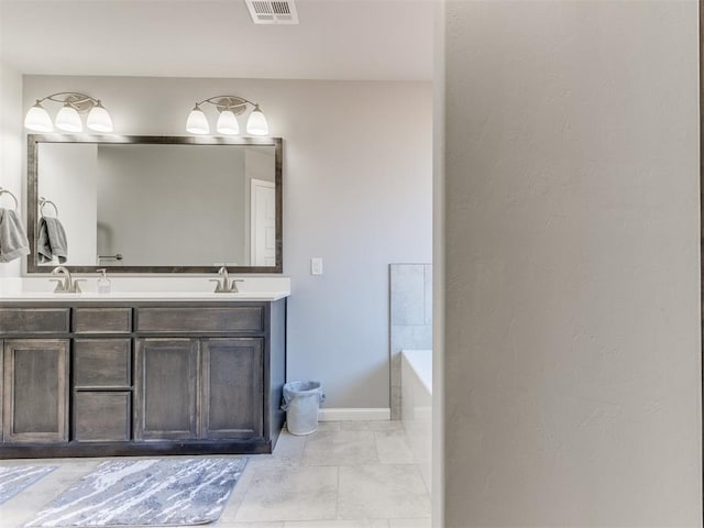 bathroom with baseboards, visible vents, double vanity, a sink, and a bathtub