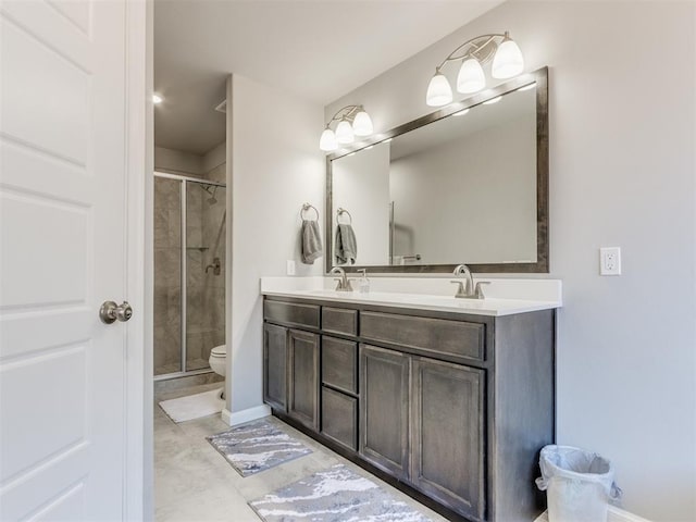 full bathroom featuring a shower stall, toilet, double vanity, and a sink