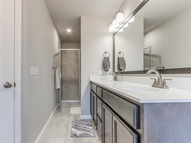 bathroom featuring a shower stall, double vanity, baseboards, and a sink