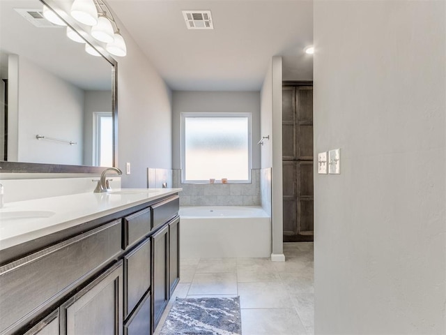 bathroom with tile patterned flooring, visible vents, a garden tub, and a sink