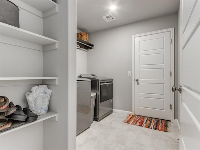 washroom featuring visible vents, baseboards, laundry area, and washing machine and clothes dryer