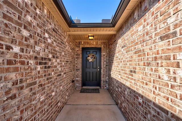 view of exterior entry featuring brick siding