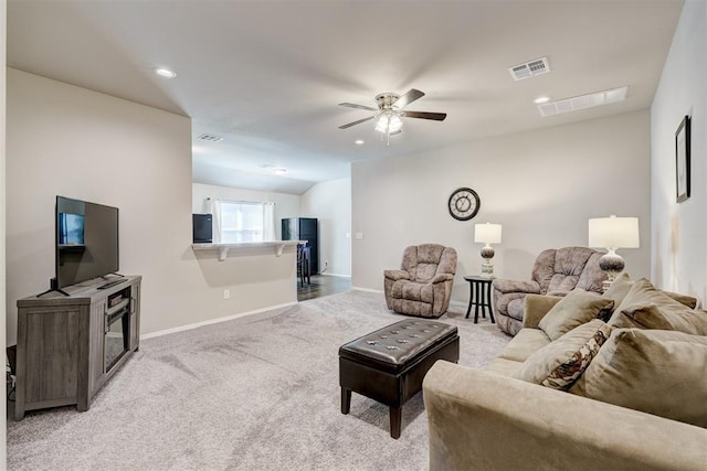 living area with visible vents, light colored carpet, baseboards, and ceiling fan