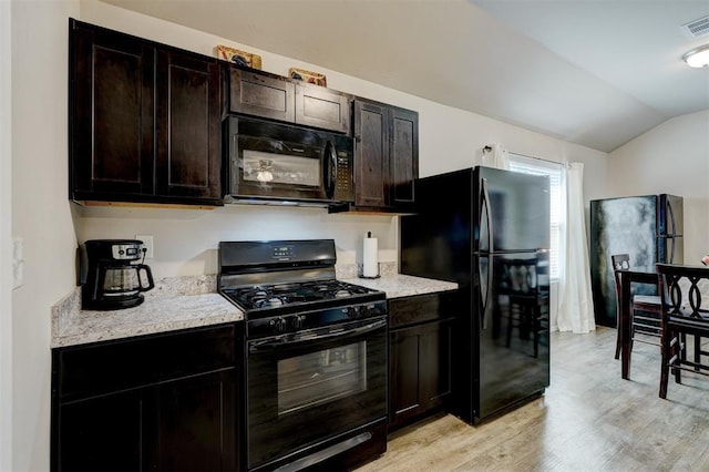 kitchen with light wood-style flooring, black appliances, light countertops, and lofted ceiling