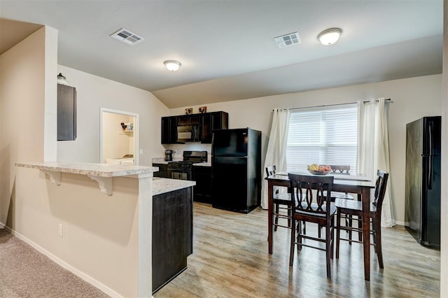 kitchen featuring a breakfast bar, black appliances, a peninsula, and visible vents