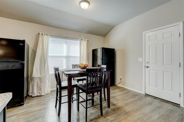 dining space with baseboards, light wood-type flooring, and lofted ceiling