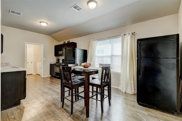 dining area featuring vaulted ceiling, light wood-style flooring, and visible vents