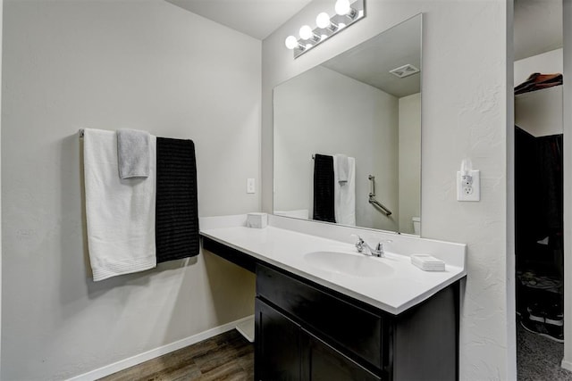 bathroom with vanity, visible vents, wood finished floors, and baseboards