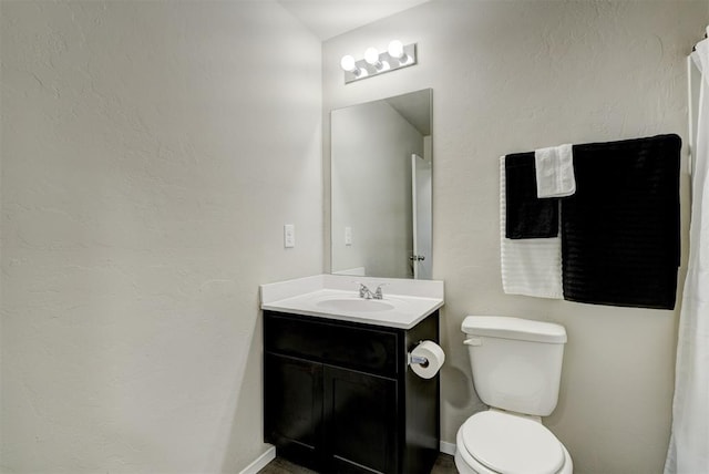 bathroom with toilet, vanity, and baseboards