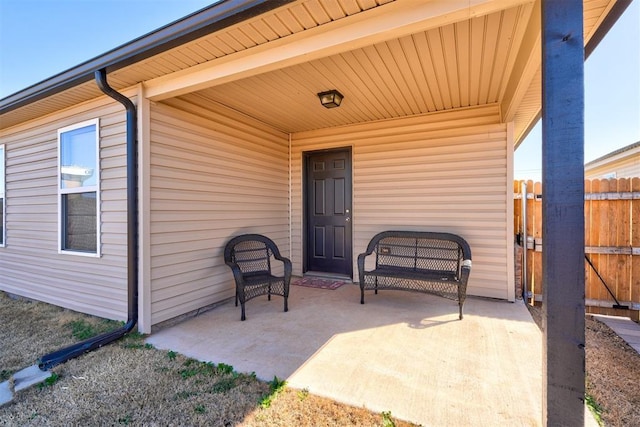 view of exterior entry with a patio area and fence