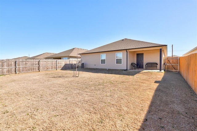 back of house with a patio area, a fenced backyard, a lawn, and roof with shingles