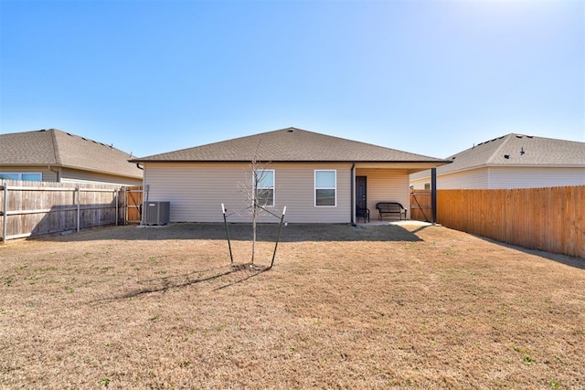 rear view of house with a yard, central AC unit, and a fenced backyard