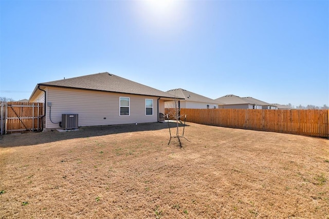 back of property featuring central AC unit, a yard, and a fenced backyard