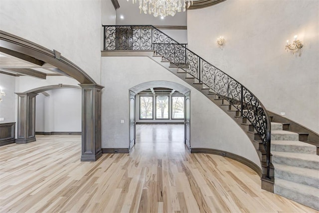 foyer featuring a notable chandelier, wood finished floors, stairway, arched walkways, and decorative columns