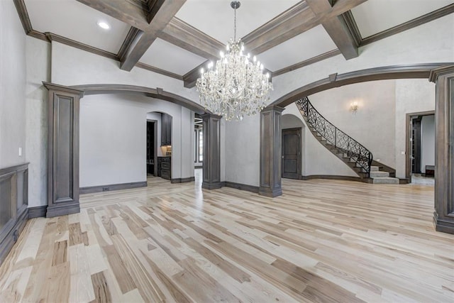 unfurnished living room with light wood-style flooring, arched walkways, and coffered ceiling