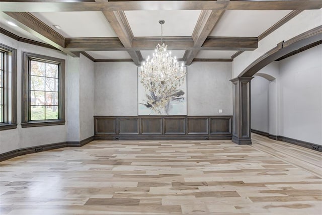 unfurnished dining area featuring beam ceiling, light wood-style flooring, arched walkways, and coffered ceiling