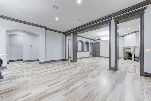 unfurnished living room featuring light wood-style floors, a fireplace, arched walkways, and baseboards