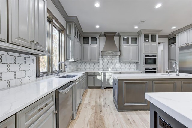 kitchen with a sink, custom range hood, stainless steel appliances, and gray cabinetry