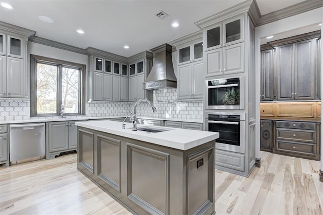 kitchen featuring gray cabinets, custom range hood, a sink, stainless steel appliances, and light countertops