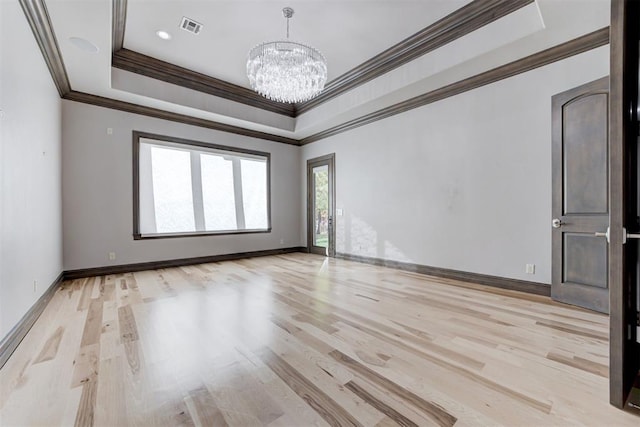 spare room with a notable chandelier, visible vents, light wood finished floors, and a raised ceiling