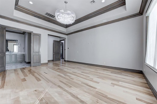 unfurnished bedroom featuring a raised ceiling, light wood-style flooring, a notable chandelier, and visible vents