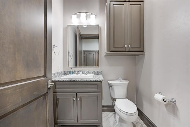 half bathroom with baseboards, toilet, and vanity