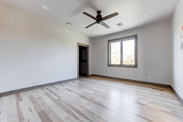 unfurnished room featuring a ceiling fan, light wood-style floors, visible vents, and baseboards