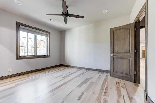 unfurnished room with baseboards, visible vents, light wood finished floors, and ceiling fan