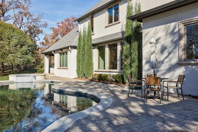 back of house with a patio, outdoor dining area, a fenced in pool, and stucco siding