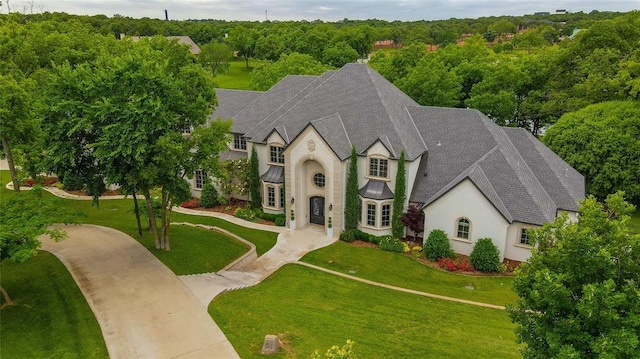 2747 Walking Woods Trl, Edmond, OK 73049 - view of front facade featuring stucco siding, a shingled roof, a front yard, a forest view, and a standing seam roof