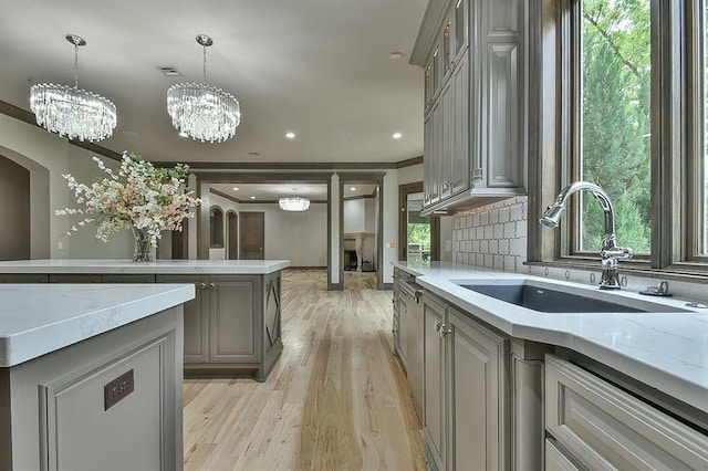 2747 Walking Woods Trl, Edmond, OK 73049 - kitchen featuring gray cabinets, a sink, light wood-type flooring, healthy amount of natural light, and crown molding
