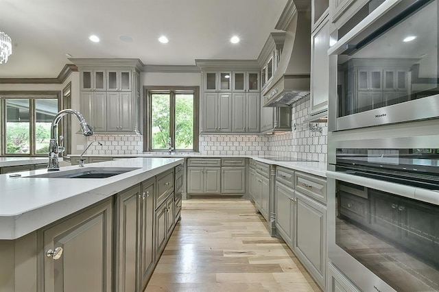 2747 Walking Woods Trl, Edmond, OK 73049 - kitchen featuring gray cabinetry, a sink, crown molding, custom range hood, and stainless steel microwave