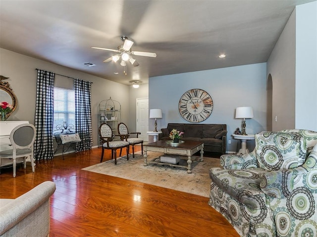 living area with wood finished floors, baseboards, visible vents, arched walkways, and ceiling fan