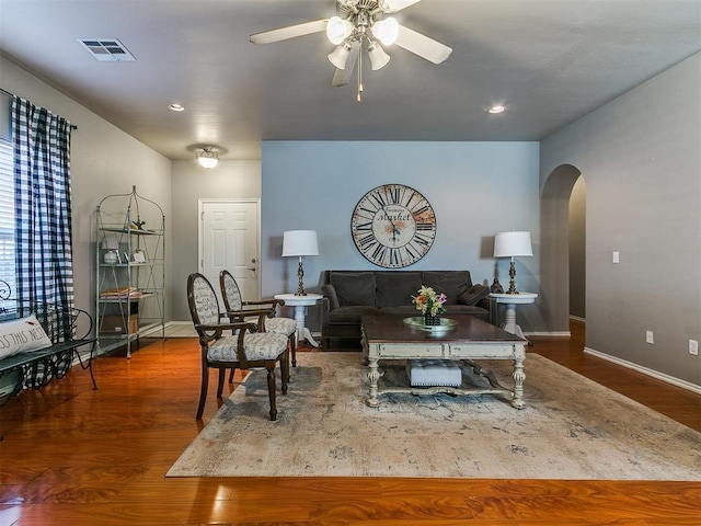 living area with wood finished floors, baseboards, visible vents, arched walkways, and ceiling fan