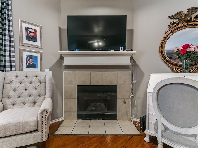 living area with wood finished floors and a tile fireplace