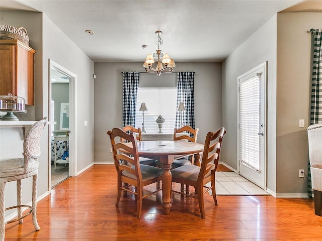 dining area featuring light wood finished floors, a chandelier, and baseboards