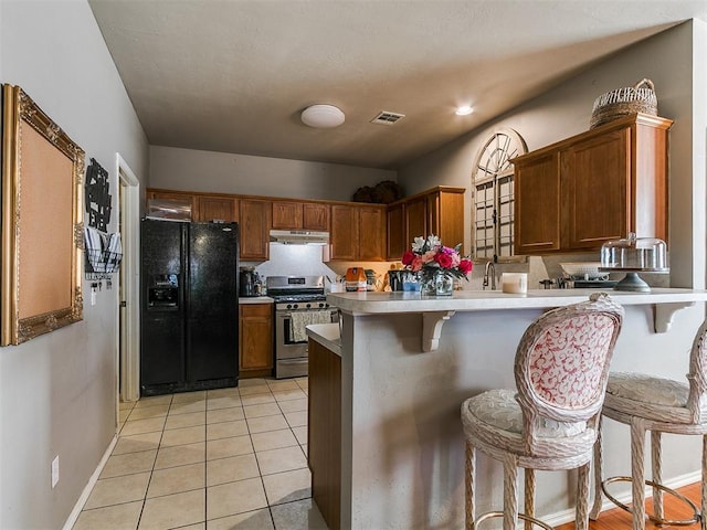 kitchen featuring visible vents, light tile patterned floors, a peninsula, black fridge with ice dispenser, and gas stove