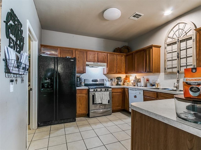 kitchen with visible vents, under cabinet range hood, dishwasher, black fridge, and stainless steel gas range