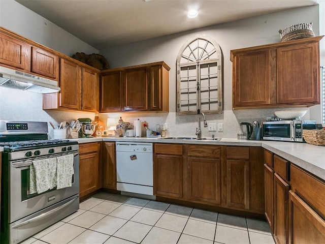 kitchen featuring stainless steel range with gas cooktop, under cabinet range hood, dishwasher, light countertops, and a sink